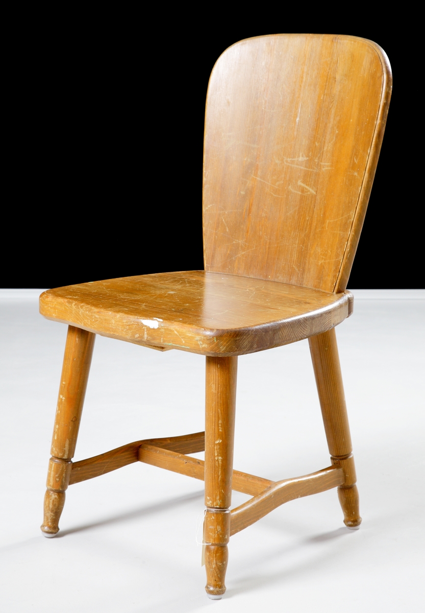 En enkel stol i fernissad furu med hel rygg och fyra ben.
