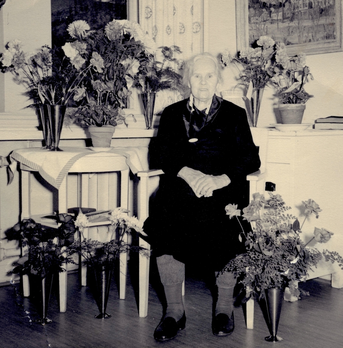 Hulda Hansson (1876 - 1975) blir uppvaktad med blommor på Brattåshemmet, okänt årtal. Hon arbetade som hushållerska hos konsul Kindal på Vasagatan i Göteborg. Han ägde Gumperts bokhandel (se Hembygdsskrift nr 13). Efter pensioneringen bosatte hon sig i föräldrahemmet Vommedal Västergård "Sväs", där Brattåsgården nu ligger.