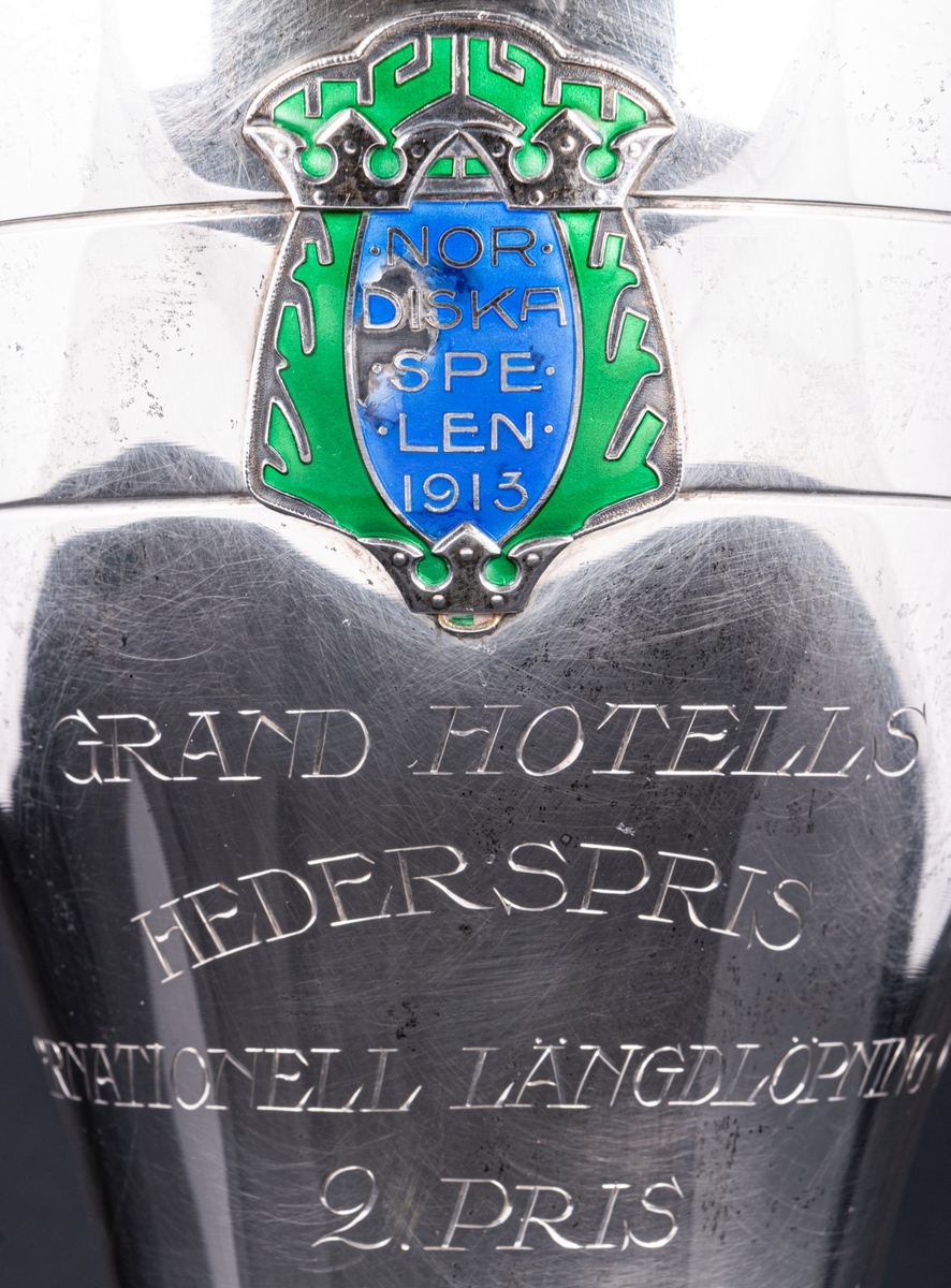 Pokal i silver. Grand Hotells Hederspris. internationell längdlöpning 60 km.
2:a pris.
Nordiska spelen 1913.