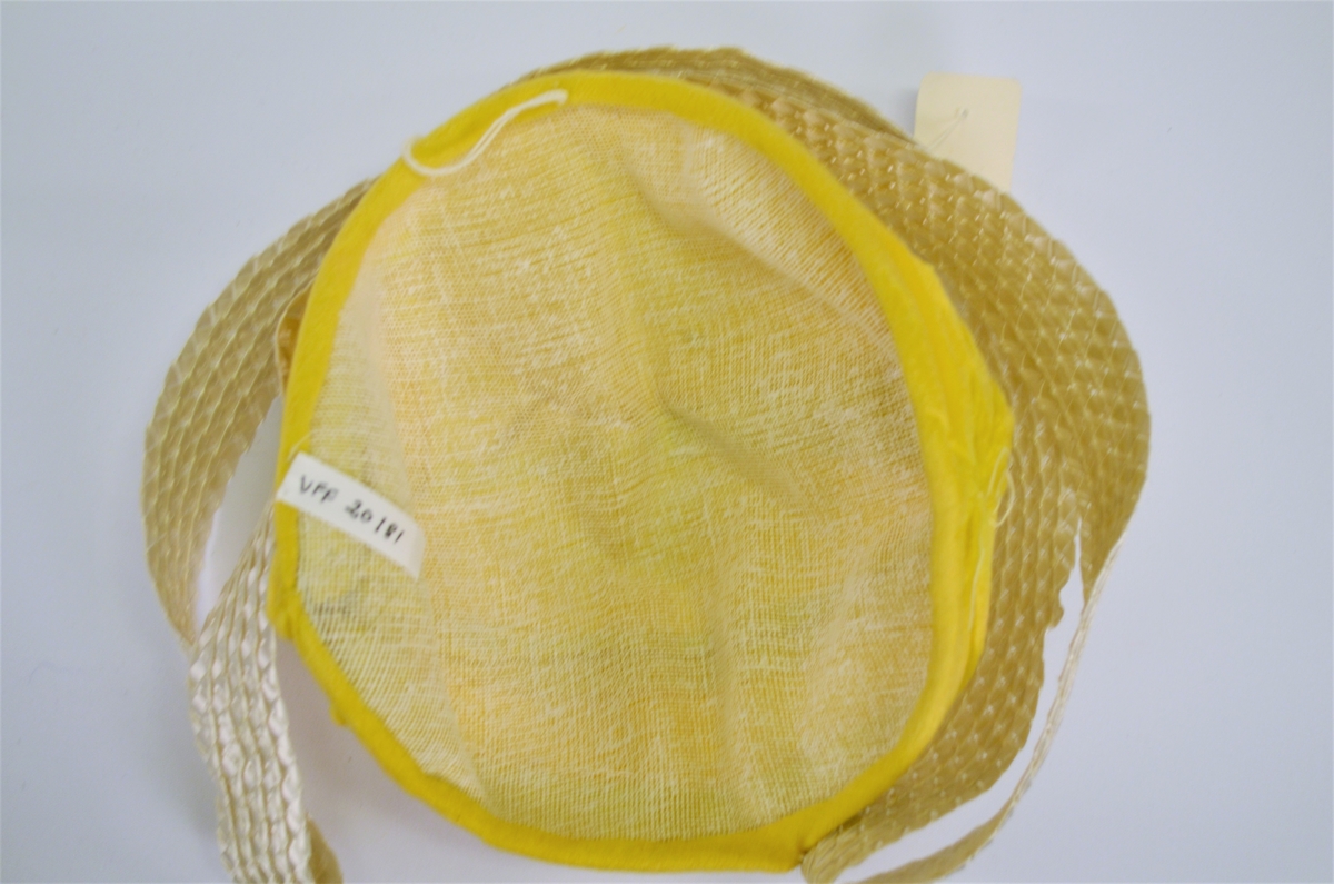 Hatt i gul velour, fóra med stiv netting. Laust "metallband" med merkelapp 8225 Made in Sweitzerland.  42,-