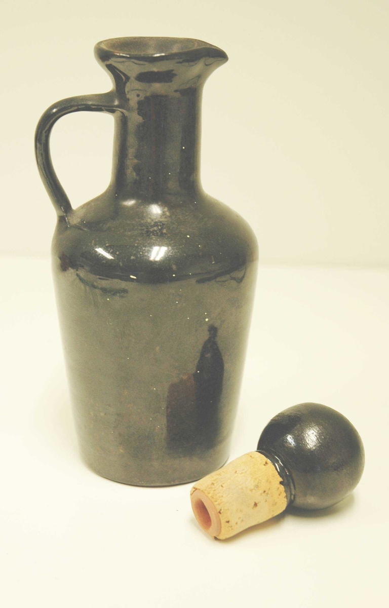 Svart keramikkflaske med kork. Korken har kule, også i keramikk.