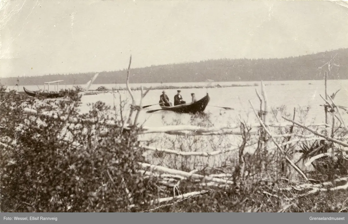 Elvebåt med tre personer på Pasvikelva, ved  Salmijärvi. Den bakerste mannen er muligens doktor A. B. Wessel.