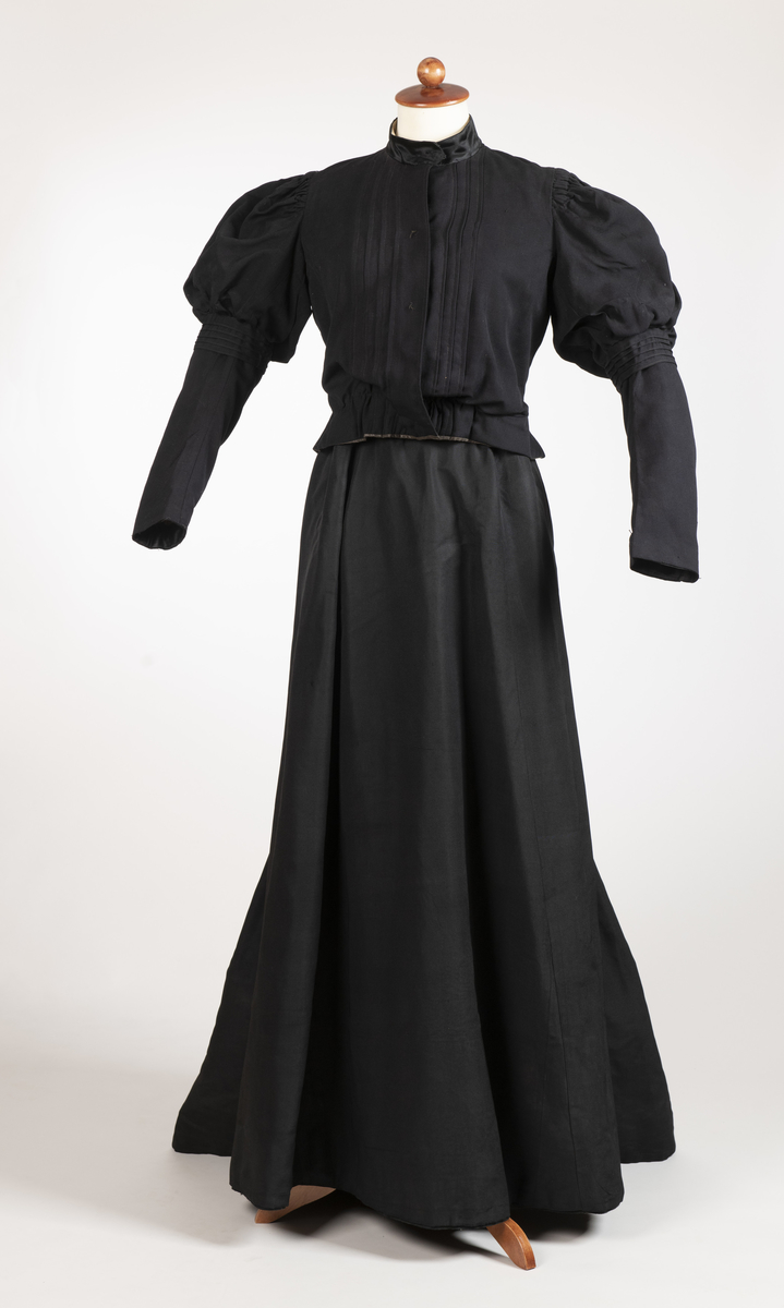 Kjole i to deler, bestående av skjørt og kjoleliv av tynt, sort ullstoff. 