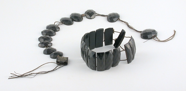 Innehållande tvenne armband samt ett trasigt halsband av av svarta glaspärlor (ovala i rektangulära facetter).