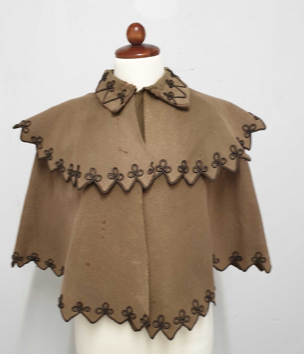 Brun cape av ullfilt, med lissebroderi langs kantene nederst, på kragen og langs pyntekragen over skuldrene.