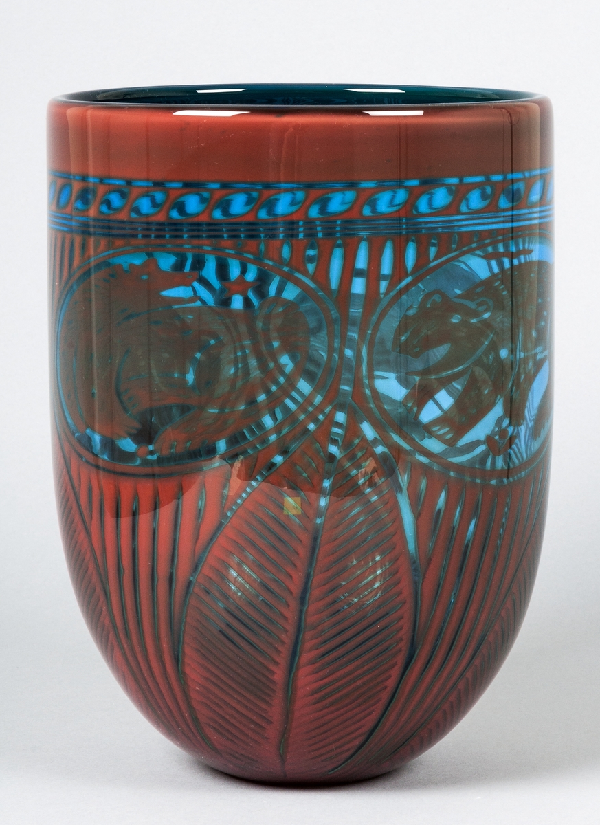 Vas av glas "Fyra björnar", formgiven av Gunnar Cyrén och tillverkad hos Orrefors. Röd dekor på blå botten. Tre "medaljonger" med björnar på övre delen. Nedtill bladdekor.