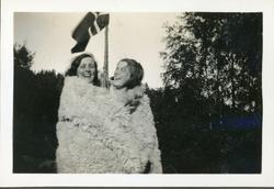 To jenter i skinnfell foran flaggstang. Ingelsrudsjøen. Trol