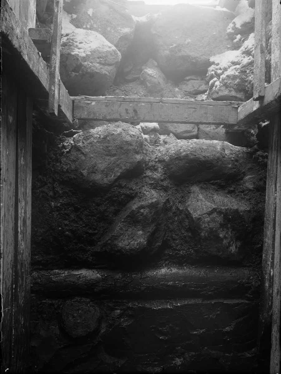 Utgrävning av Helgeandshuset, liggande timmer som bas för stensyll, Uppsala 1925