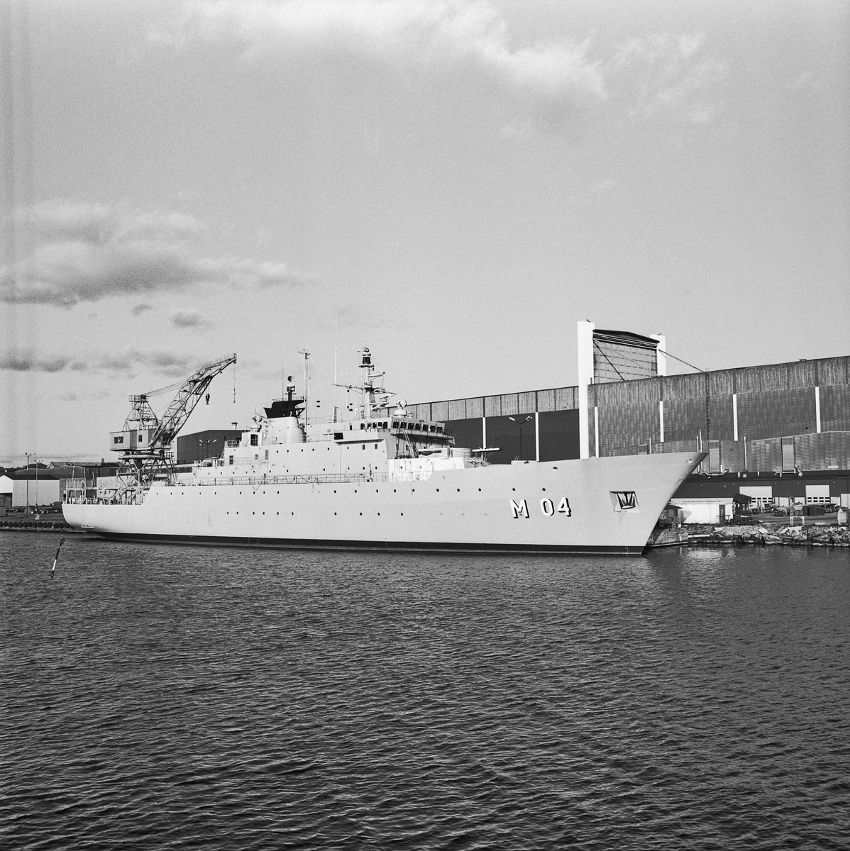 Minfartyget Carlskrona ligger förtöjt framför den stora skrovhallen på Karlskronavarvet.