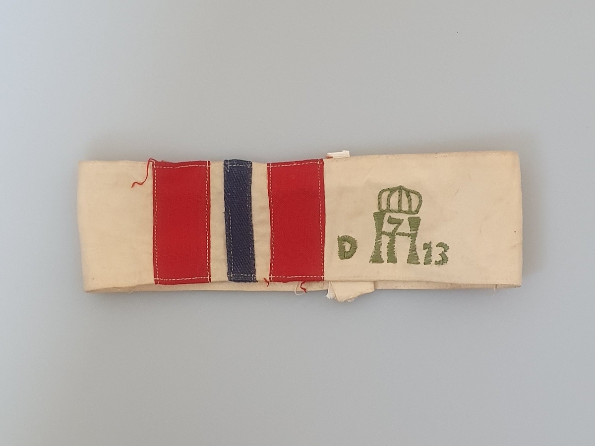 I tillegg til flaggstriper, H7-logo med krone over, og med D på venstre side og 13 på høyre side. Logoen er opprinnelige stemplet på stoffet, men deretter brodert med grønn tråd.