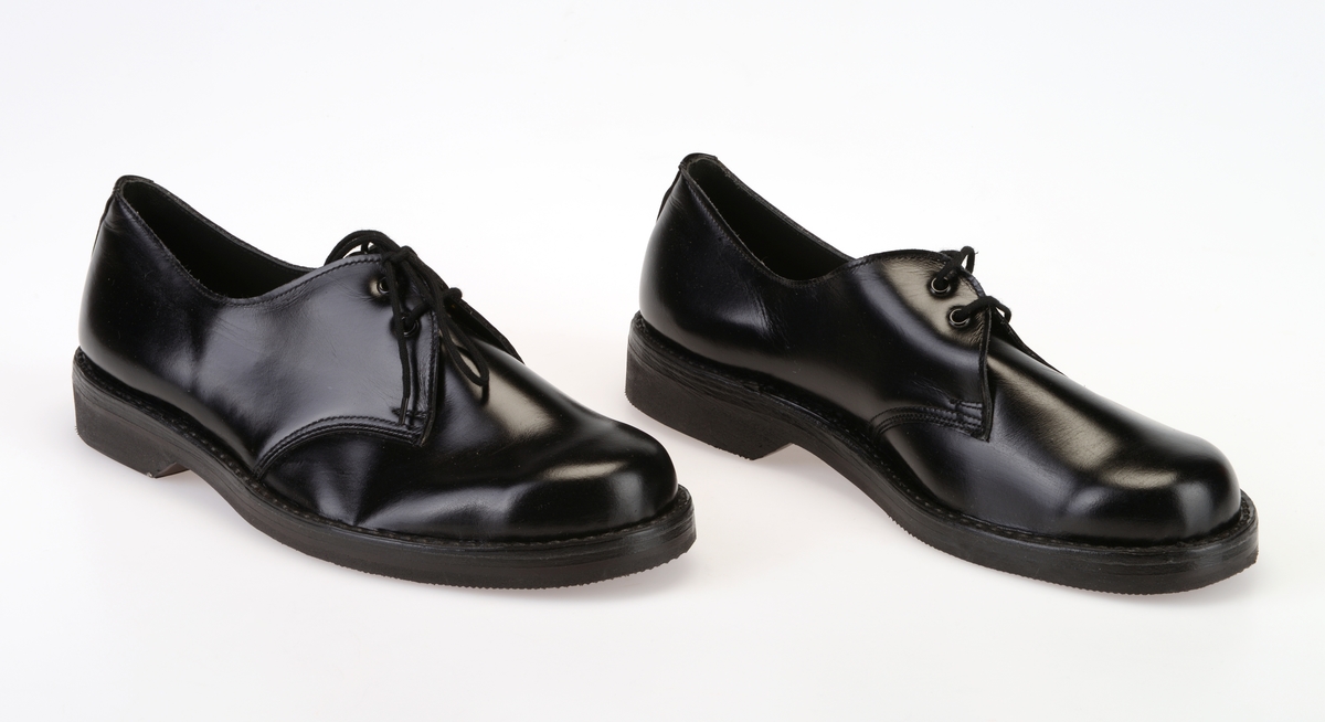 Et par barnesko i størrelse 37 i skoeske med silkepapir. Skoene er i svart skinn med såler av svart gummi. Yttersålen har rutemønster og buet mønster. Ved hælen står det "Bever" i sålen. Skoene er randsydde. I front er det 2 par hull med maljer for snøring. Under snøringen er det en enkel tunge av svart skinn. Skoene har svarte, runde skolisser. Skoene har innersåle av lær. De er foret med hvit tekstil i den fremre delen og grått lær (eller kunstlær?) i den bakre delen. Skoene ligger i en skoeske av papp som er stiftet sammen. På den ene kortsiden er det trykt på fabrikkens navn, varemerke og logo samt artikkelnummer og størrelse. Logoen er en sirkel med en Nord-pil igjennom. Logo og tekst er i rødt med påstemplet artikkelnummer og påskrevet størrelse i svart. Skoene er ikke brukt.