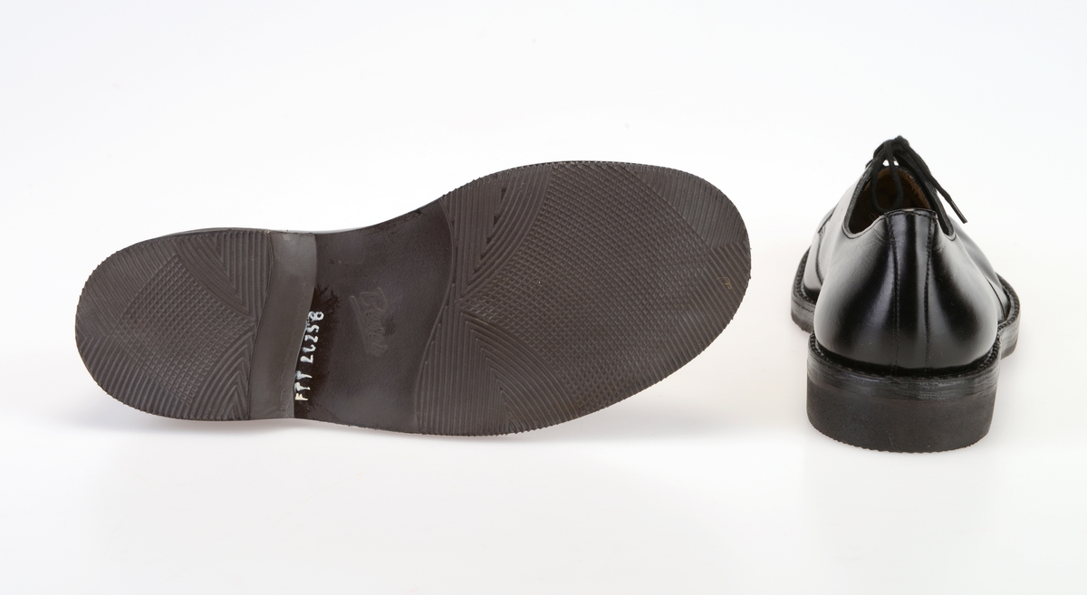 Et par barnesko i størrelse 37 i skoeske med silkepapir. Skoene er i svart skinn med såler av svart gummi. Yttersålen har rutemønster og buet mønster. Ved hælen står det "Bever" i sålen. Skoene er randsydde. I front er det 2 par hull med maljer for snøring. Under snøringen er det en enkel tunge av svart skinn. Skoene har svarte, runde skolisser. Skoene har innersåle av lær. De er foret med hvit tekstil i den fremre delen og grått lær (eller kunstlær?) i den bakre delen. Skoene ligger i en skoeske av papp som er stiftet sammen. På den ene kortsiden er det trykt på fabrikkens navn, varemerke og logo samt artikkelnummer og størrelse. Logoen er en sirkel med en Nord-pil igjennom. Logo og tekst er i rødt med påstemplet artikkelnummer og påskrevet størrelse i svart. Skoene er ikke brukt.