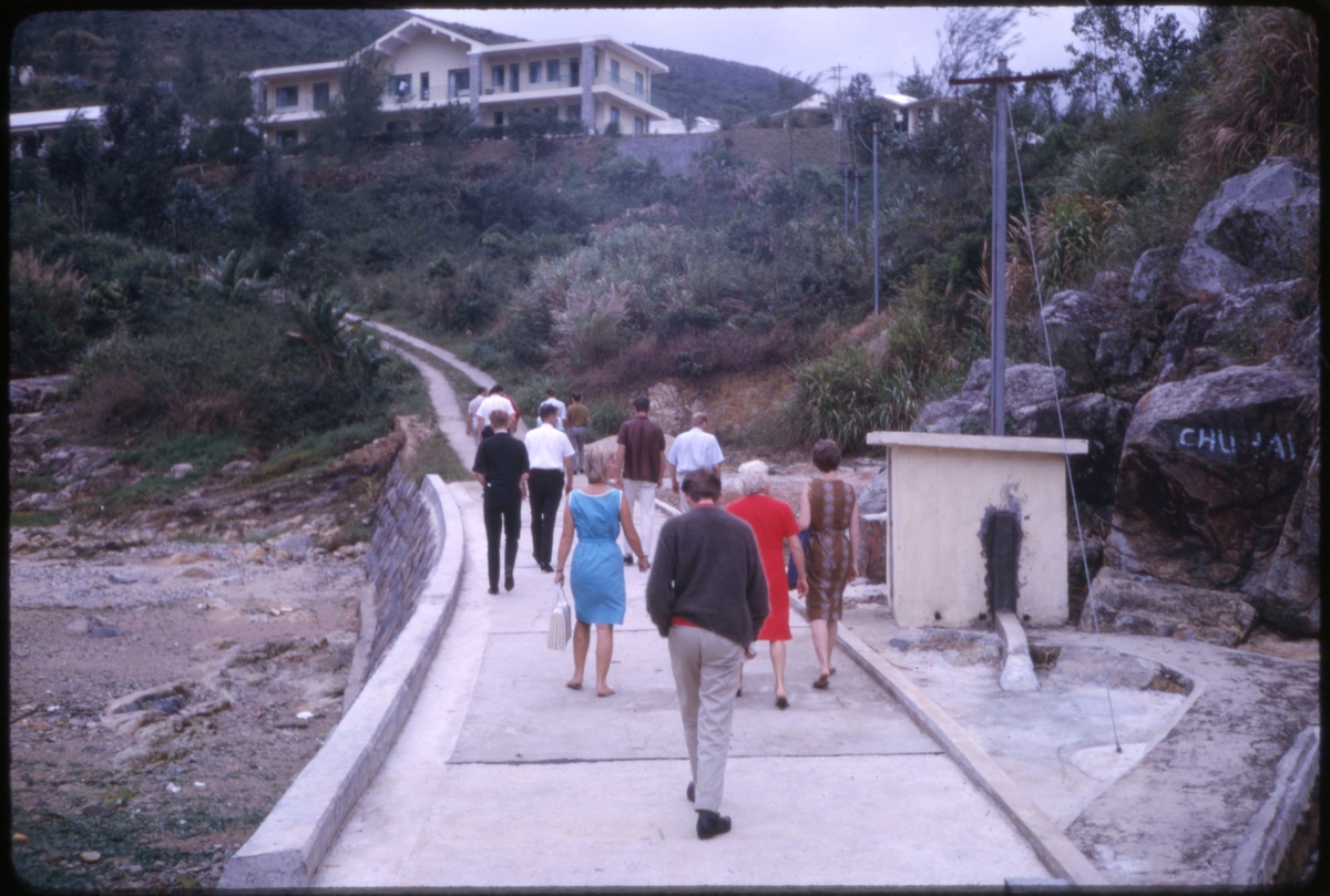Turister gående i retning bygninger på en åsside. 'Sagafjord' Around The World via Africa Cruise 1966.