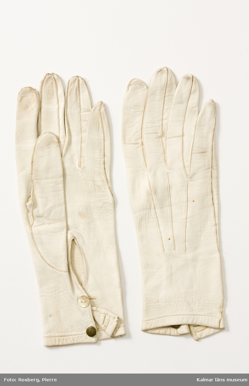 KLM 37459:26 Handskar av skinn, ett par. Två knappar för knäppning på resp handske. Handskarna av vitt, fint, glacéskinn.