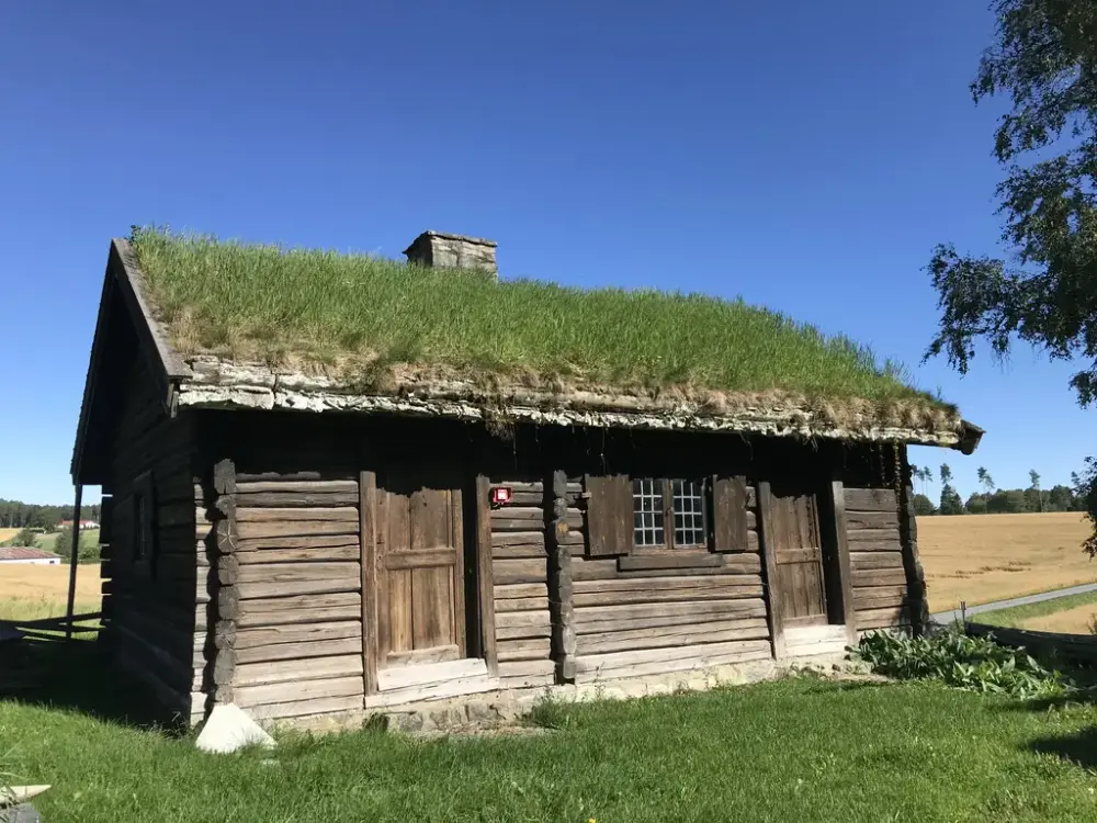 Bildet viser bryggerhuset. Huset er laftet og har torv tak.