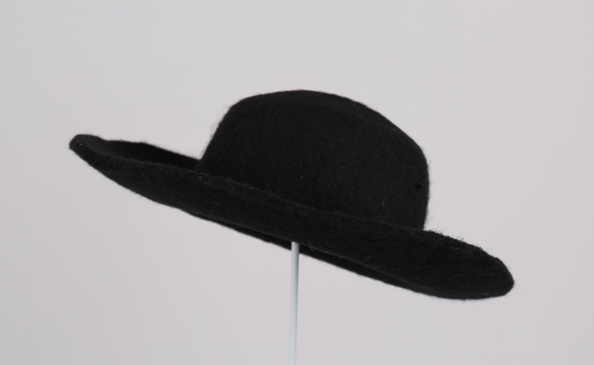 Herrehatt i tova ull, med brem og pull i eitt stykke. Hatten har rund brem, lett bøygd rundt kanten, pullen er rund med avflata topp.