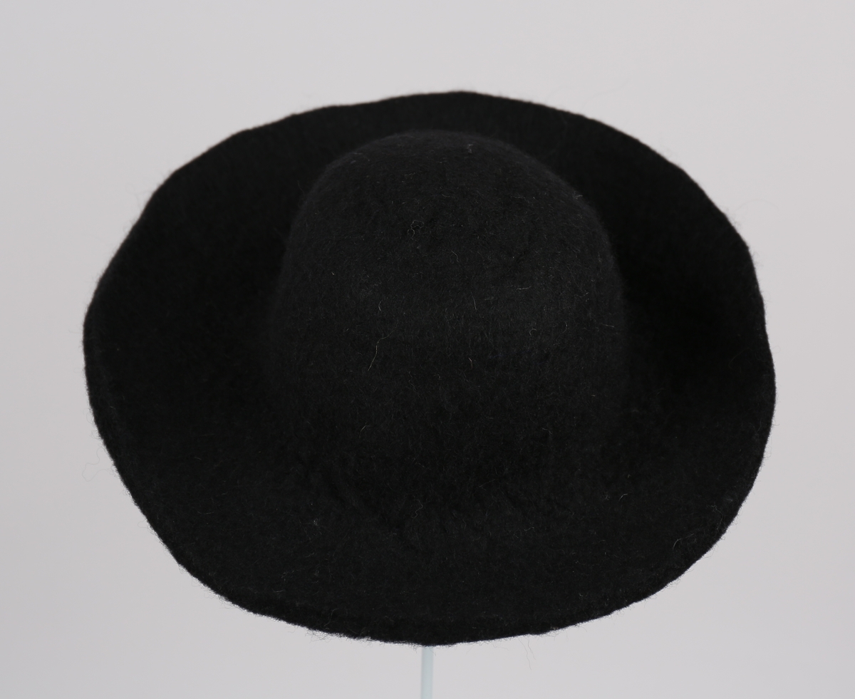 Herrehatt i tova ull, med brem og pull i eitt stykke. Hatten har rund brem, lett bøygd rundt kanten, pullen er rund med avflata topp.