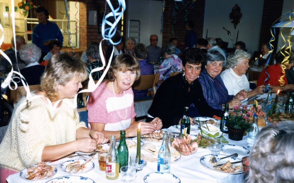 Kräftskiva i Brattåsgårdens matsal (Streteredsvägen 5) där girlanger hänger i taket, 1990-tal. Andra person från vänster: vårdbiträde Greta Nilsson och vårdbiträde Lillvi Häggsten.