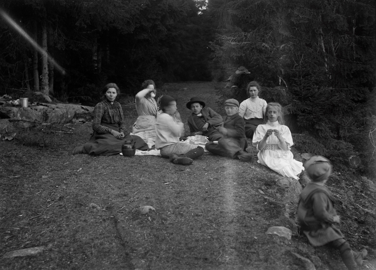 Gruppeportrett av familien Aston Eikrem på piknik i skogen.