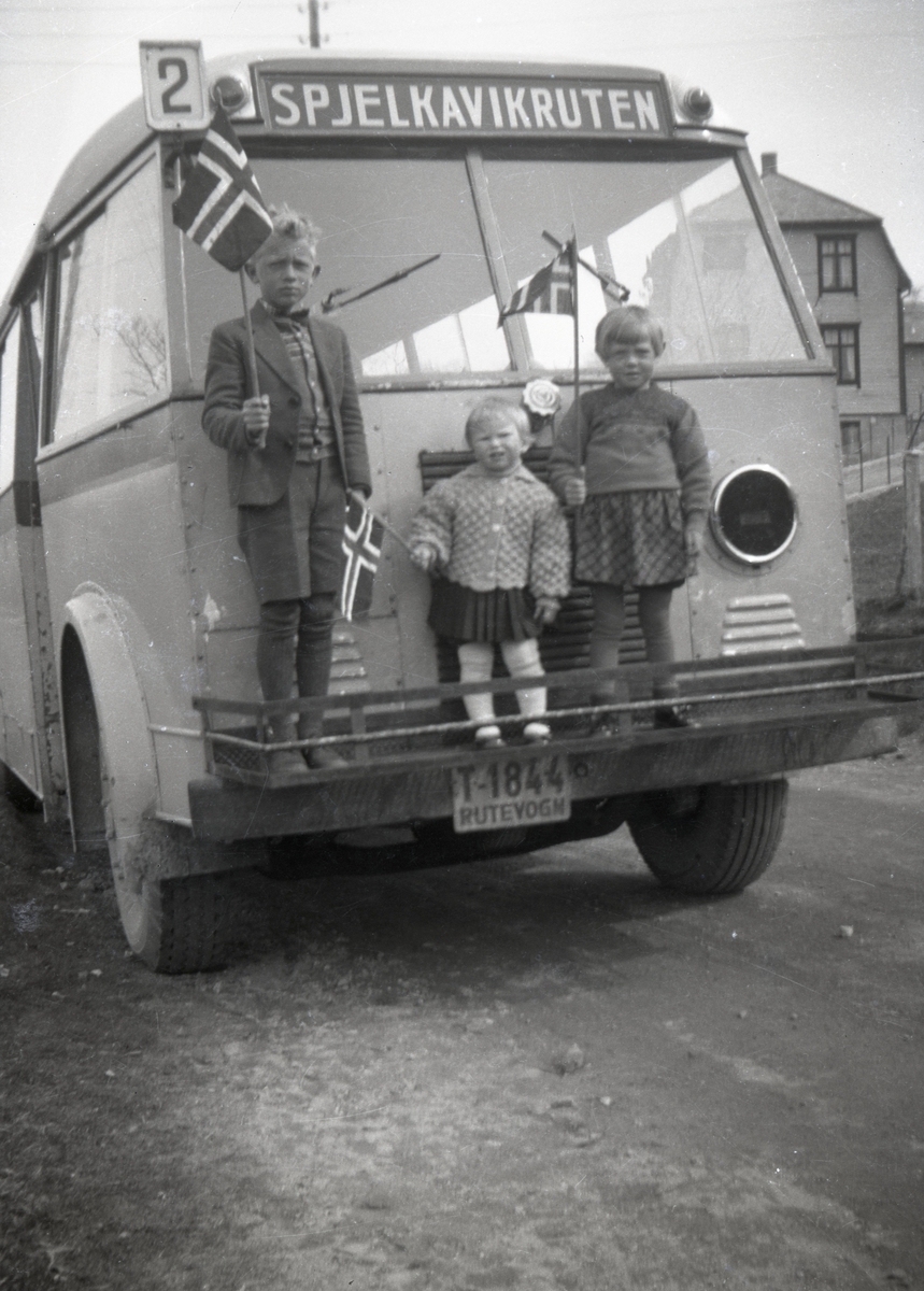 Tre barn med norske flagg står frampå rutevogna Spjelkavikruten (T-1844).