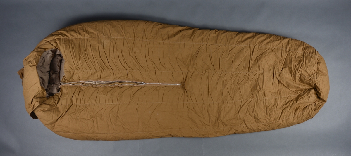 Sovepose med glidelås og trekk. Posen er sydd med halvmåneformet stykke i fotenden og rund form ved hodeenden.