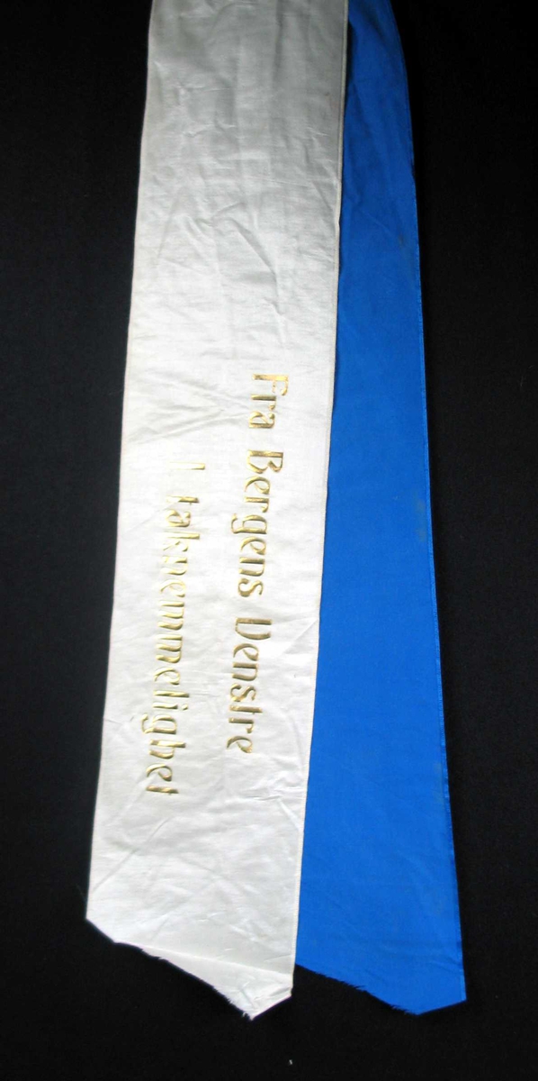 Begravelsessløyfe i hvit og blå silke med tekst i gull.