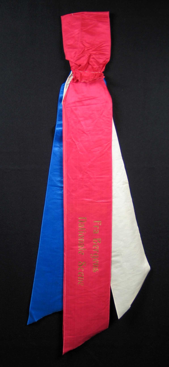 Begravelsessløyfe i rød, blå og hvit silke med tekst i gull.