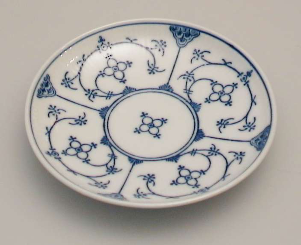 Kaffeskål  i porselen med riflet gods og blått mønster.
Stempelet har to piler i kors.