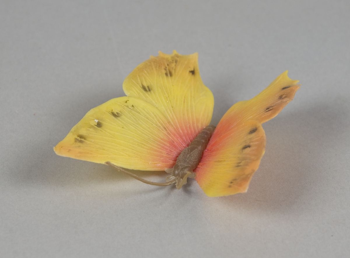 Hårspenne av plast formet som en sommerfugl. Selve hårklemmen sitter under sommerfuglkroppen.