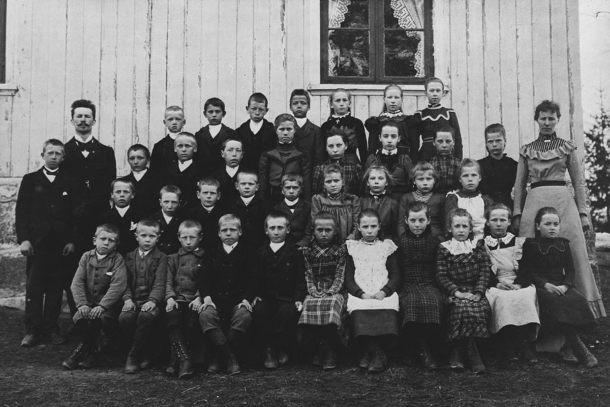 Skolebilde med barn og en lærerinne og lærer Otto Olsen, ansatt ved skolen fra 1898 - 1909