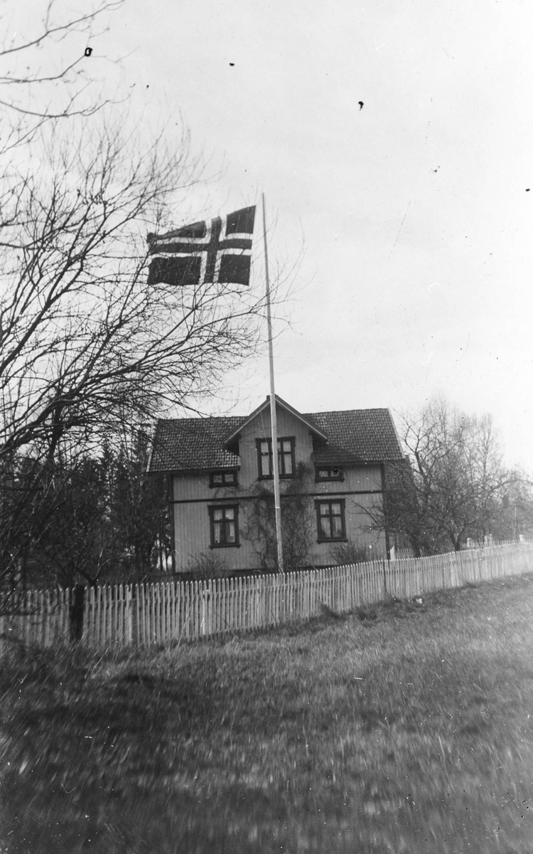 Sætre. Sveitserstilshus med stakitt og norsk flagg i flaggstangen.