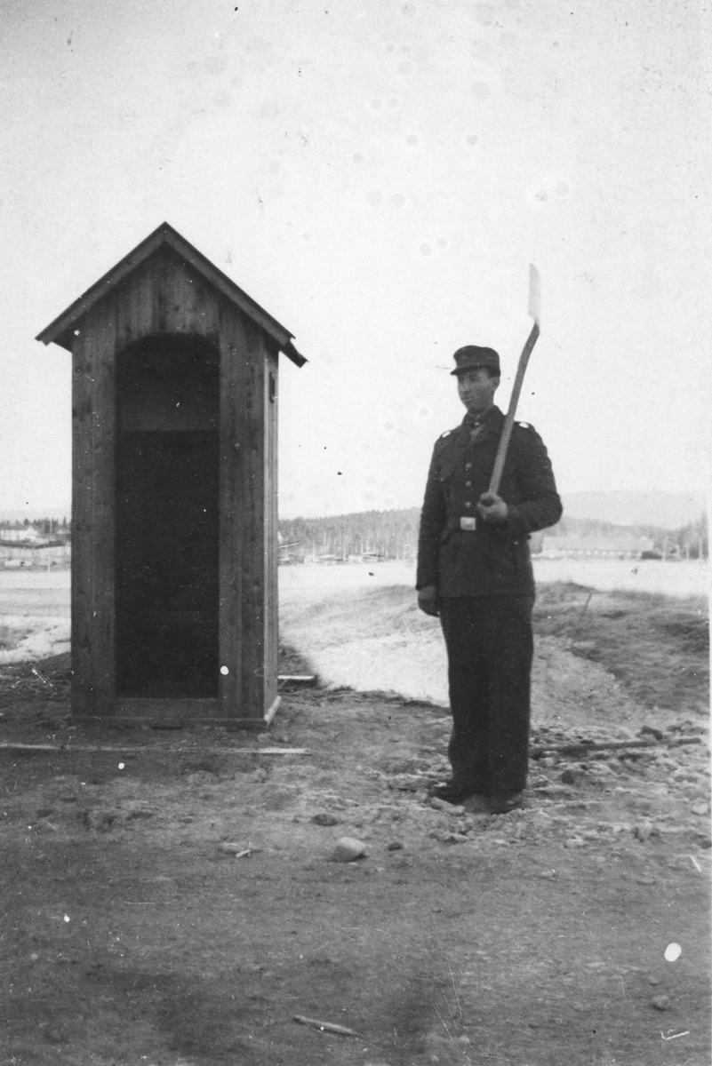 Arbeidstjeneste på Bjørkelangen høst-43. Vaktpost med spade ved skilderhuset.