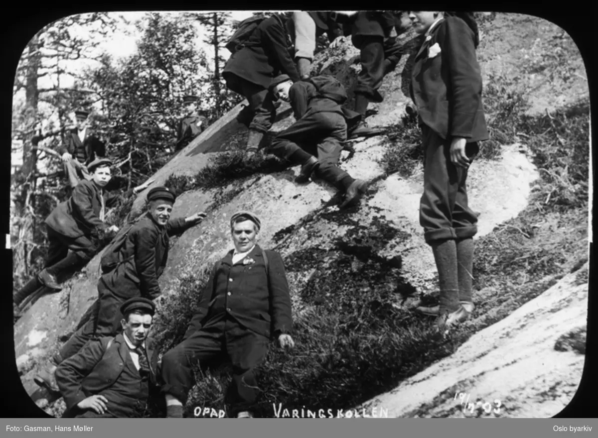 En gruppe menn og ungdommer som klyver på berget, som posering for fotografen, 19. juli 1903