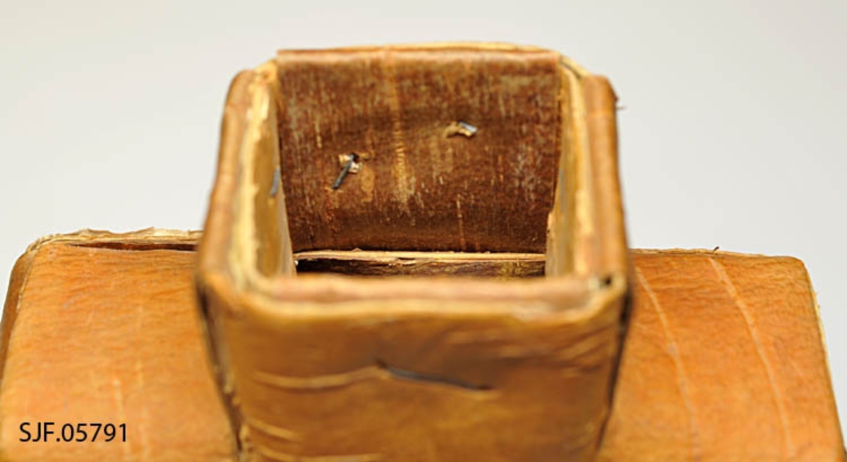 Saltflaska er flettet av never. Ved tuten er det brukt stiftemaskin for å feste nevra. Proppen er av ubehandlet bjørk. Den er laget av Mentz Åsen, Grue Finskog ca. 1963, og kjøpt inn til museet da. 