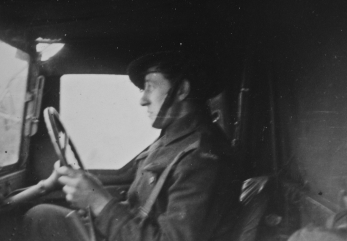 Brigadesoldat med hjelm bak rattet på militært kjøretøy.