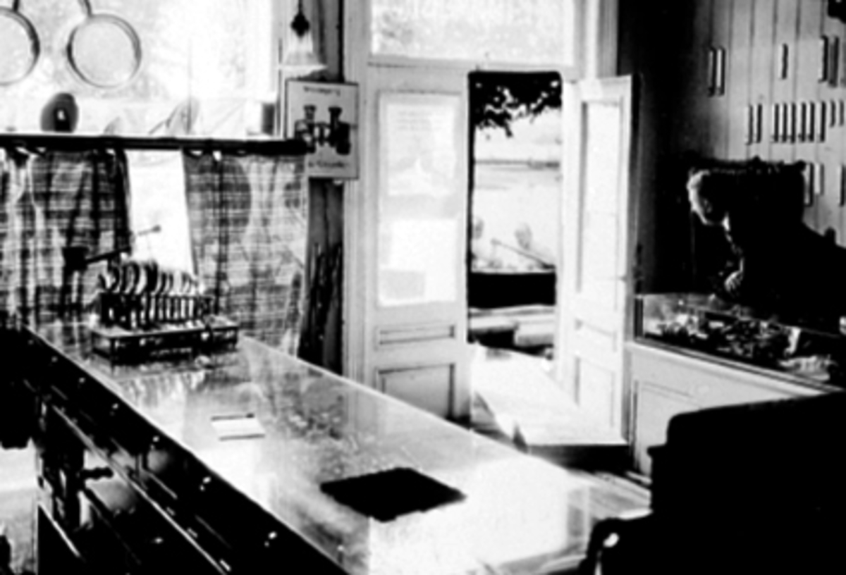Trygve Hansen, E. Hammerstads eftf. interiør fra forretningen under storflommen i 1927. Trygve Hansen bak disken. Urmakerforretning. Mjøsflom.