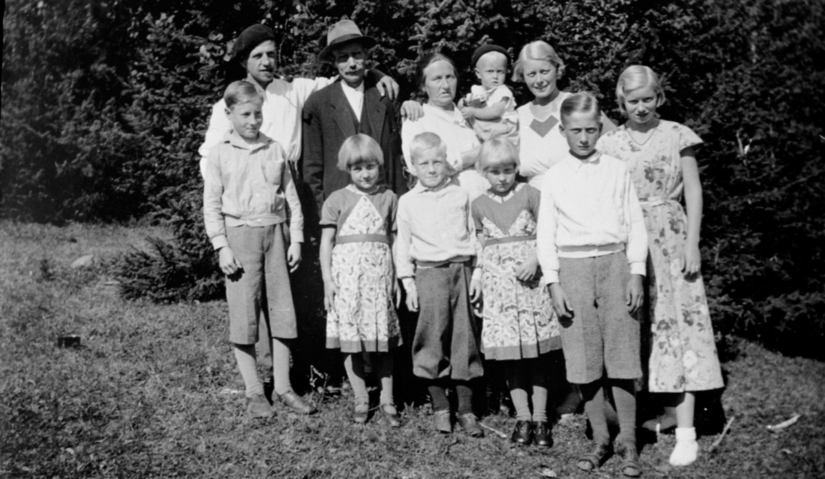 Petter Pedersen Lier (1885-1946) og kona Anne Mathea (1883-1962) med 8 av sine 12 barn på Hanastad. Husmannsplass på Hovinsholm, Helgøya.