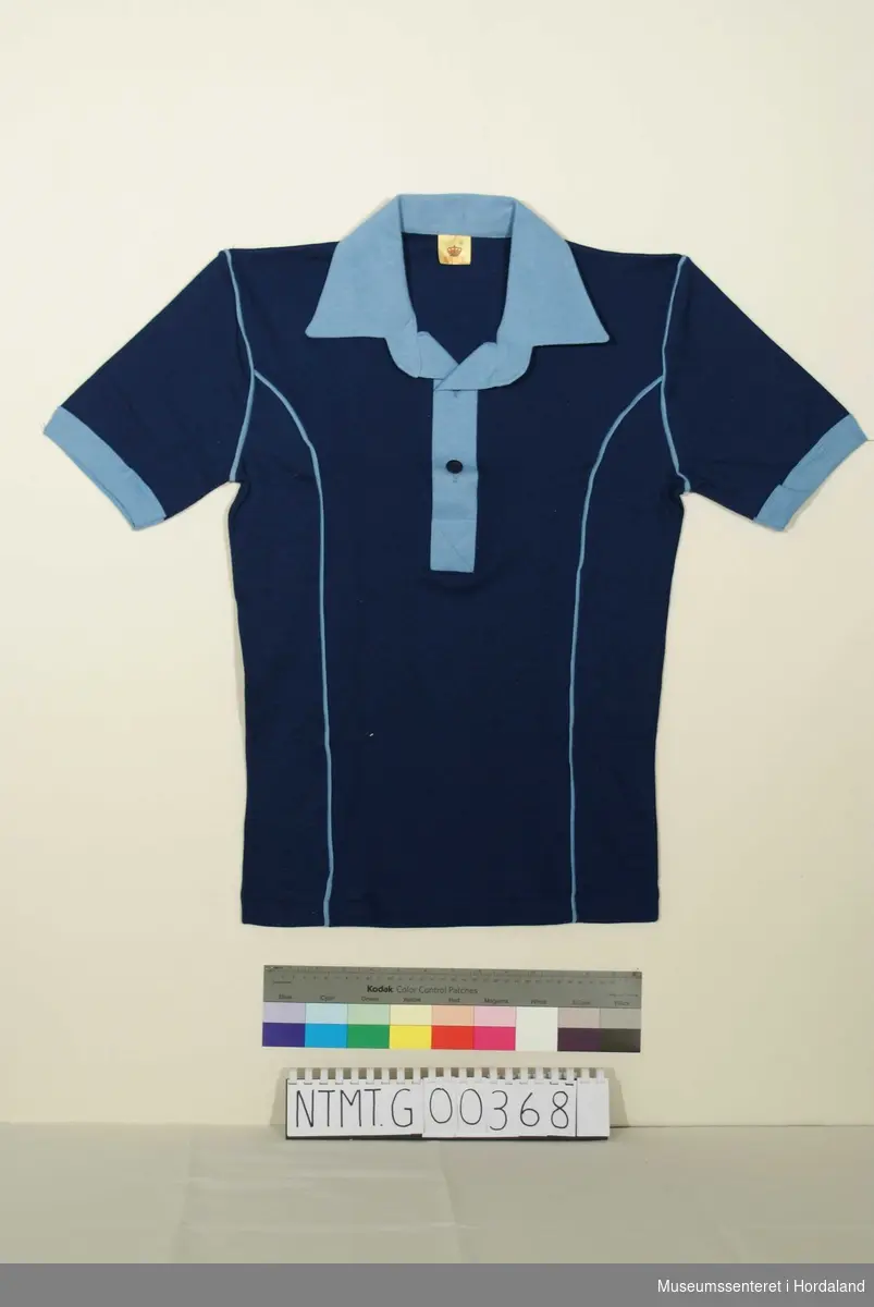 Mørk blå t-skjorte med lys blå krave, knappeåpning i hals med to knapper, lys blå knappestolpe, lys blå kantavslutning ermer.