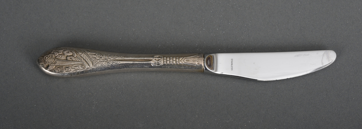 Barnekniv i stål og sølv. Skaftet er sølvbelagt med et strekt motiv av en stork (sannsynligvis).