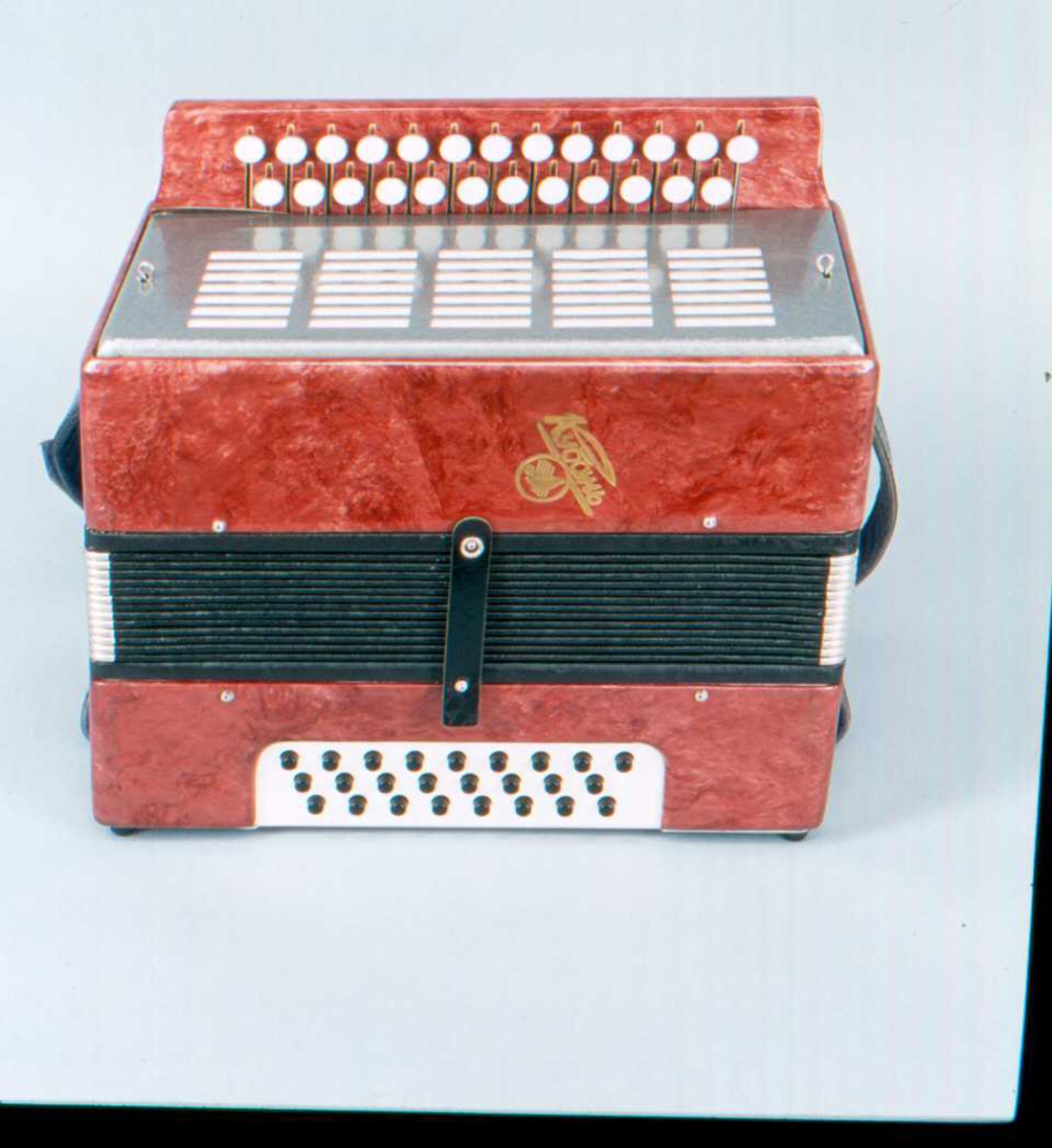 Torader med 25 (13+12) diskantknapper og 25 (9+8+8) basknapper omfång a-a''' (toner se sep. skjema)
Laget i rød celluloid med deksel i metall. Blomstermønstret tekstil i belg.
