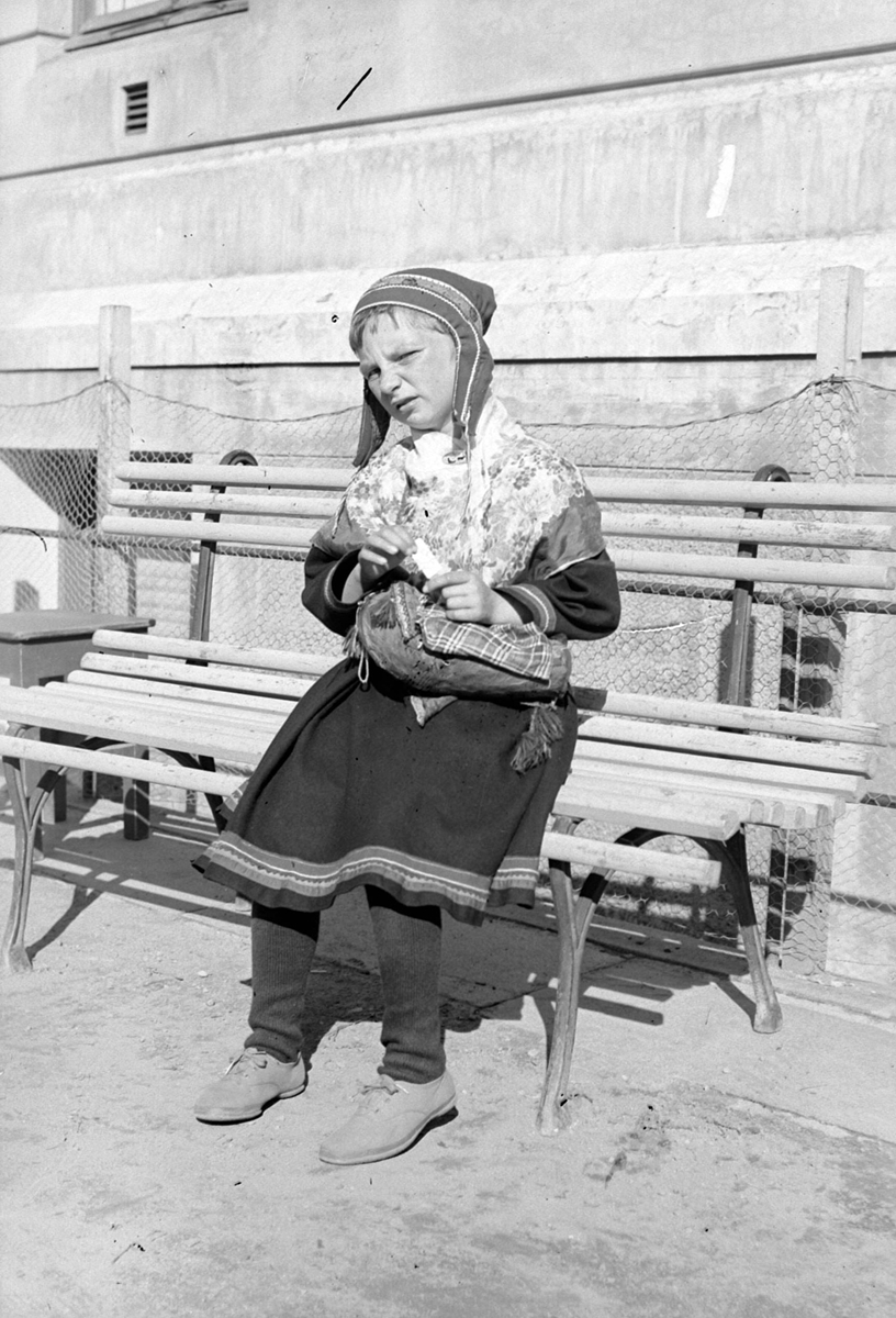 Samisk jente på benk utenfor døveskolen