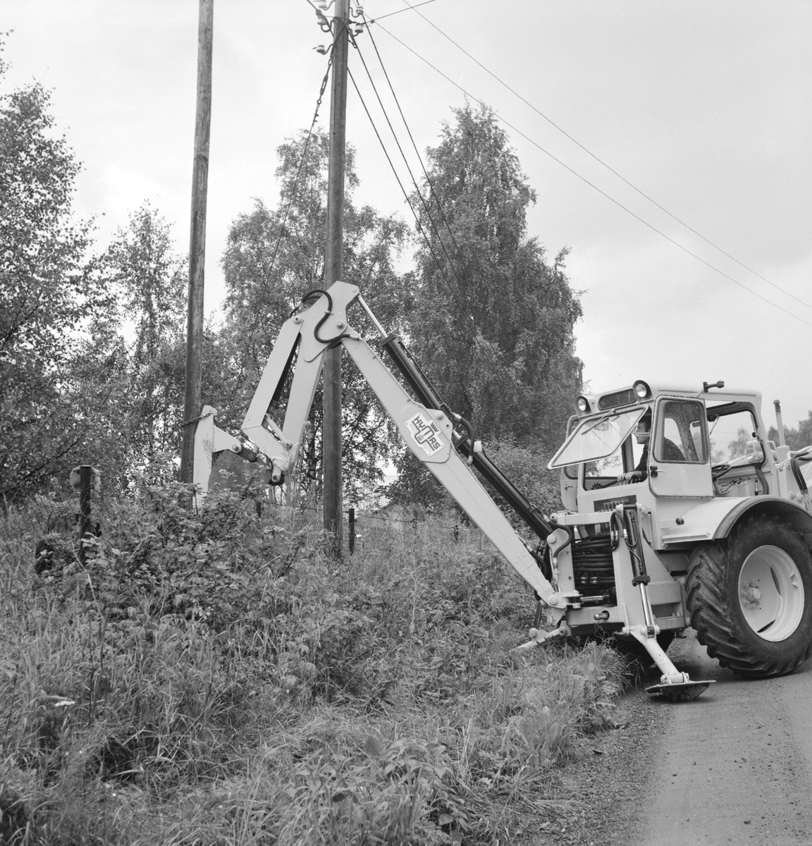 A/S Hymas, Hymas Gravemaskin. Foto for Telegrafverket. Demonstrasjon av BM Volvo, traktorgravemaskin. 17. 08. 1967. Brumunddal.  Oppsetting av telefonstolpe. 
