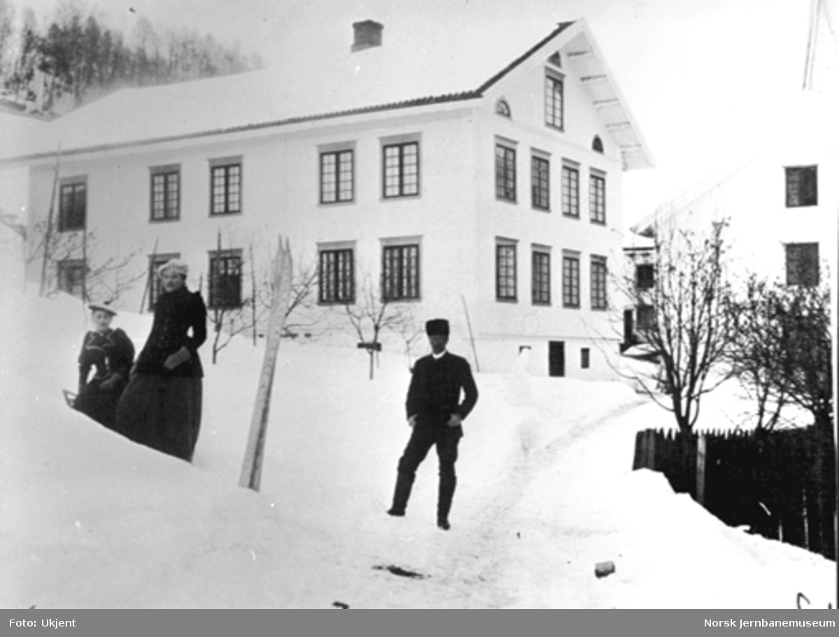 Vinterbilde av hovedbygningen på Berg gård i Ringsaker. To jenter og en mann poserer i forgrunnen