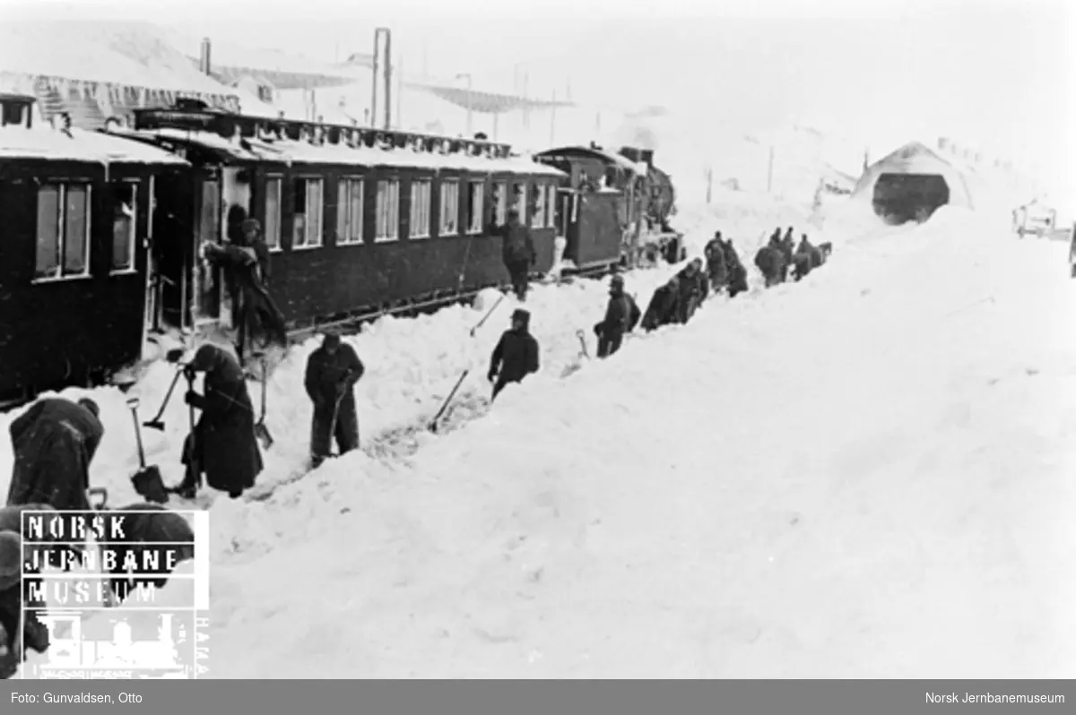 Snøryddemannskaper på Finse stasjon, hvor det står et persontog i spor 2