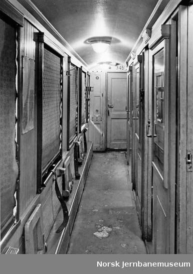 Interiørbilde fra sidegang i personvogn litra Co nr. 345; med eldre lysutstyr