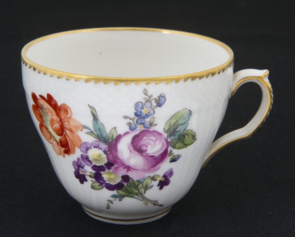 Kaffekopp i porselen med håndmalt blomsterdekor, gullkant og riflet gods. En blomst i bunn av koppen.