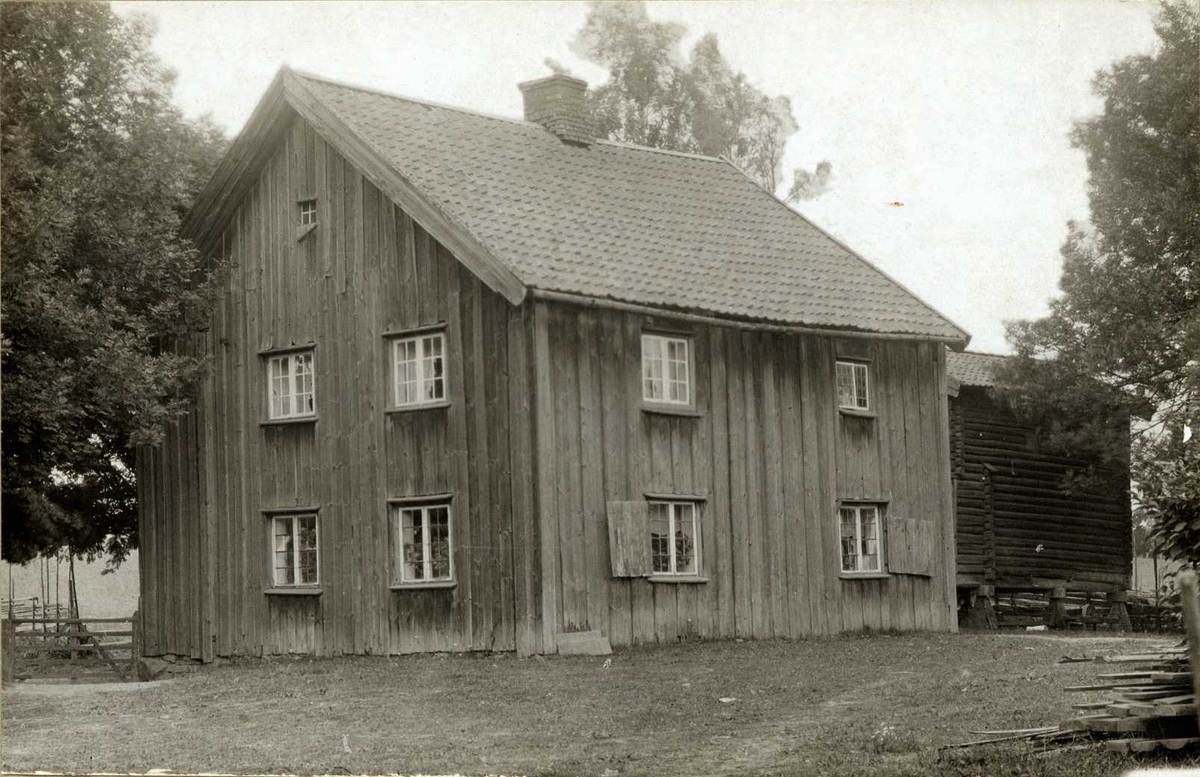 Toftner, Eidsvoll, Øvre Romerike, Akershus. Mørkt våningshus med stabbur bak.