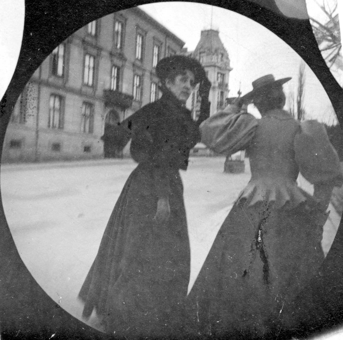 Frk. Brodkorp og en annen dame spaserer langs bygate, Oslo. Den ene holder på hatten.