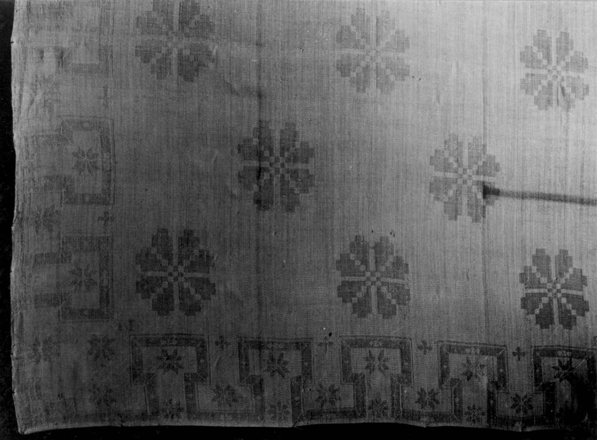 Hvit serviett i dreiel med rosettmønster, bord av knekkede bånd og stjerner. Fra begynnelsen av 1800-tallet.