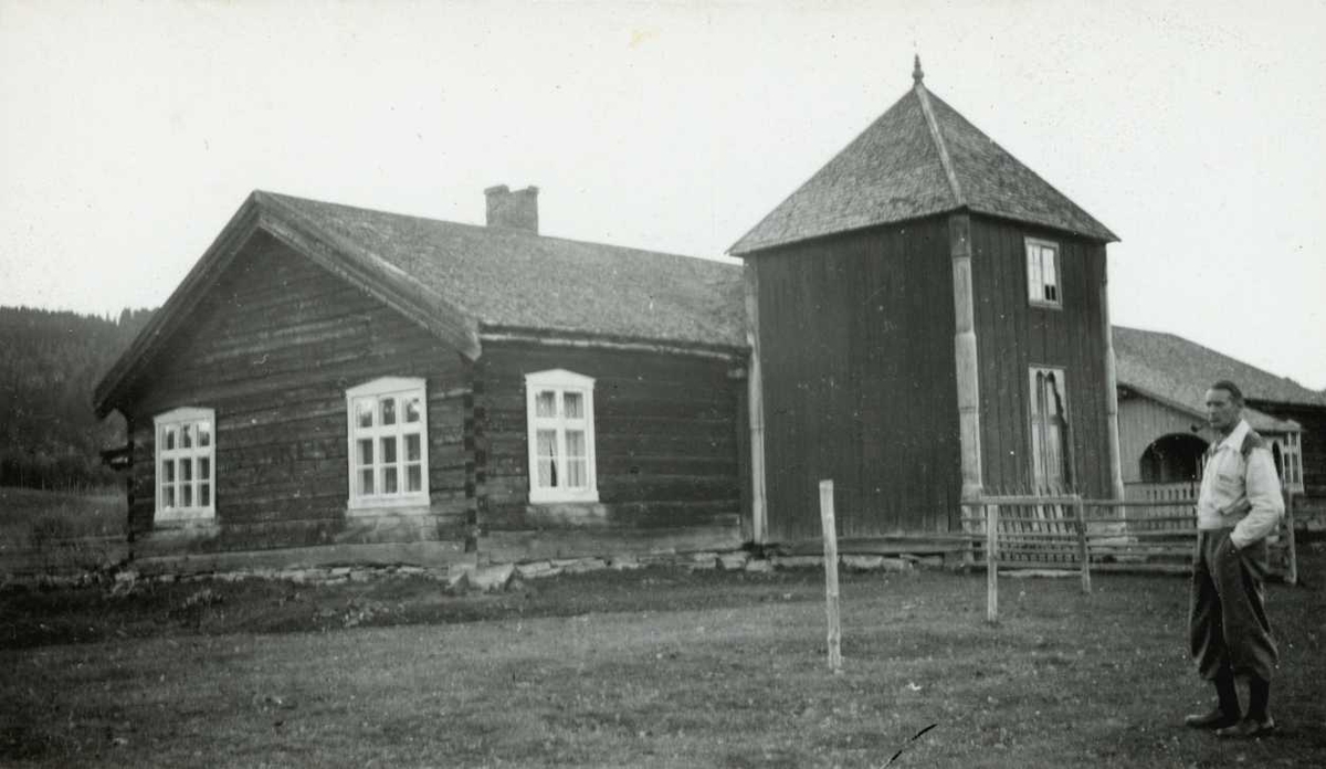 Grøtting, Rendalen, Nord Østerdal, Hedmark 1941. Mann med sekk står på gårdsplassen foran barfrøstue.